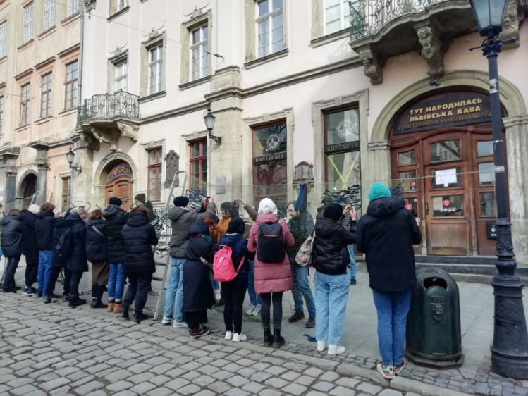 Люди плетут маскировочные сетки на площади Рынок во Львове