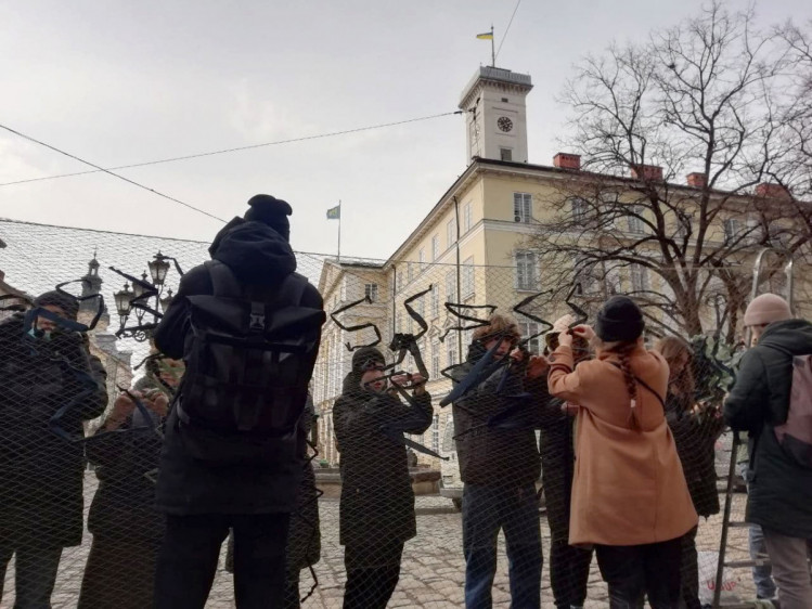 Люди плетут маскировочные сетки на площади Рынок во Львове 